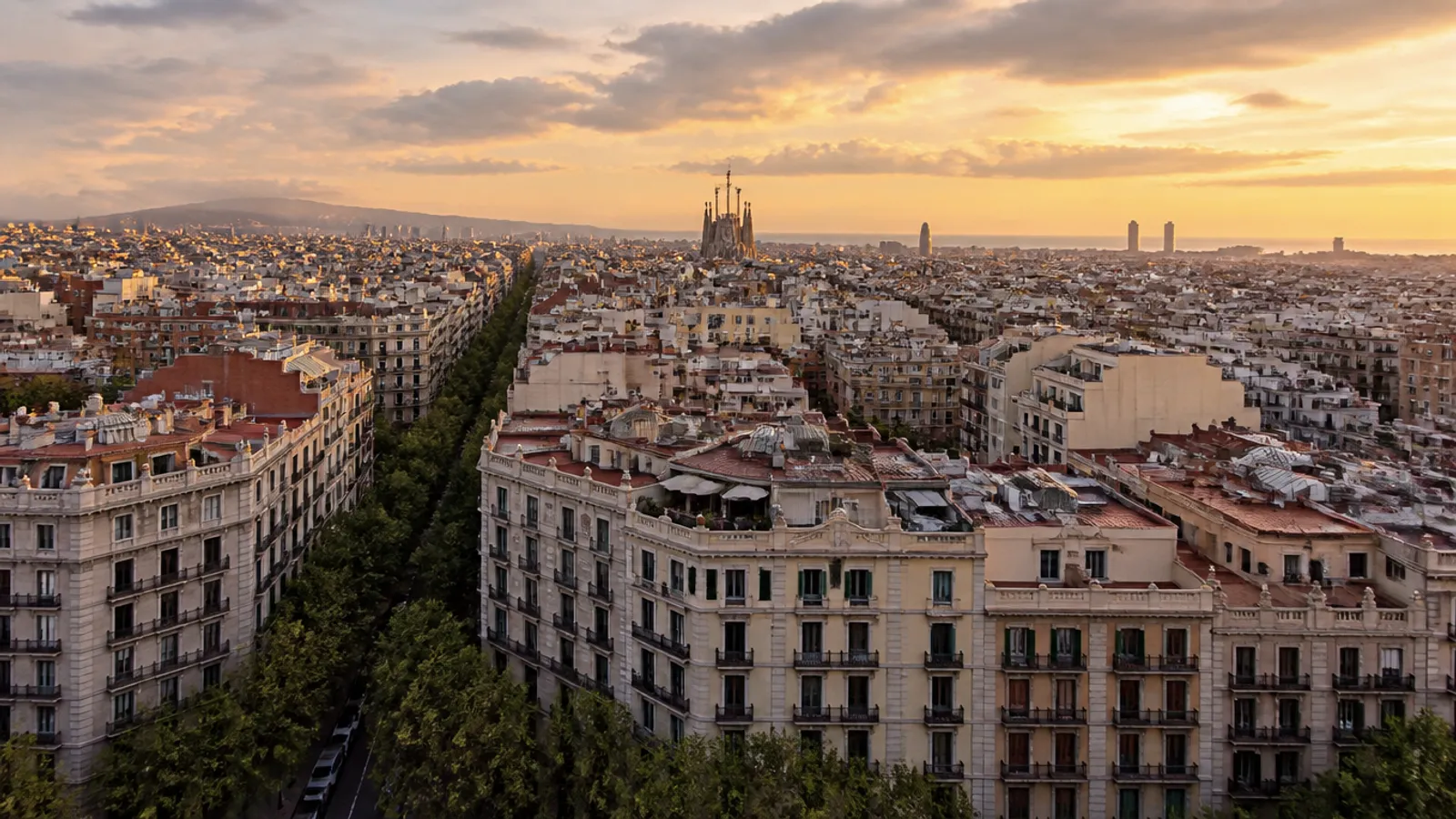 Vista real de Barcelona al atardecer: manzanas del Eixample y la Sagrada Familia al fondo, sin personas ni marcas